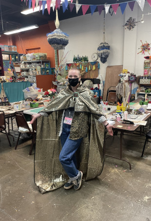 Lee Hinkle BA '24 interning at SCRAP, wearing a handmade, upcycled wizard's cape.